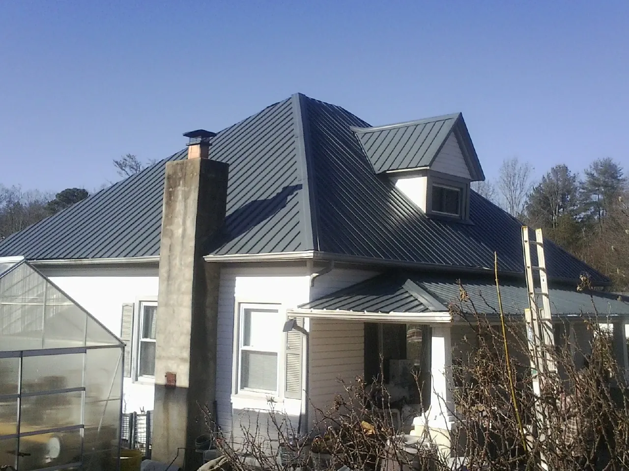 Dark blue standing seam metal roof on a white farmhouse with dormer — Slate & Tile Roof Repair by Roofing Brothers in West Warwick