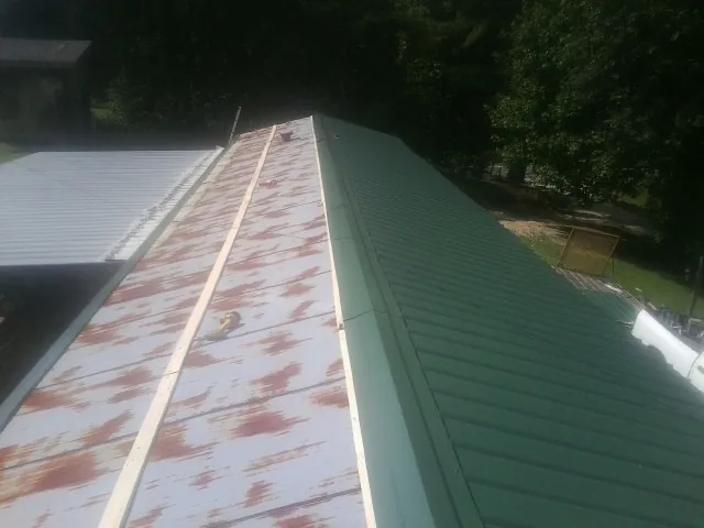Old rusted panels beside newly installed green metal roofing — Wind Damage Roof Repair by Roofing Brothers in West Warwick