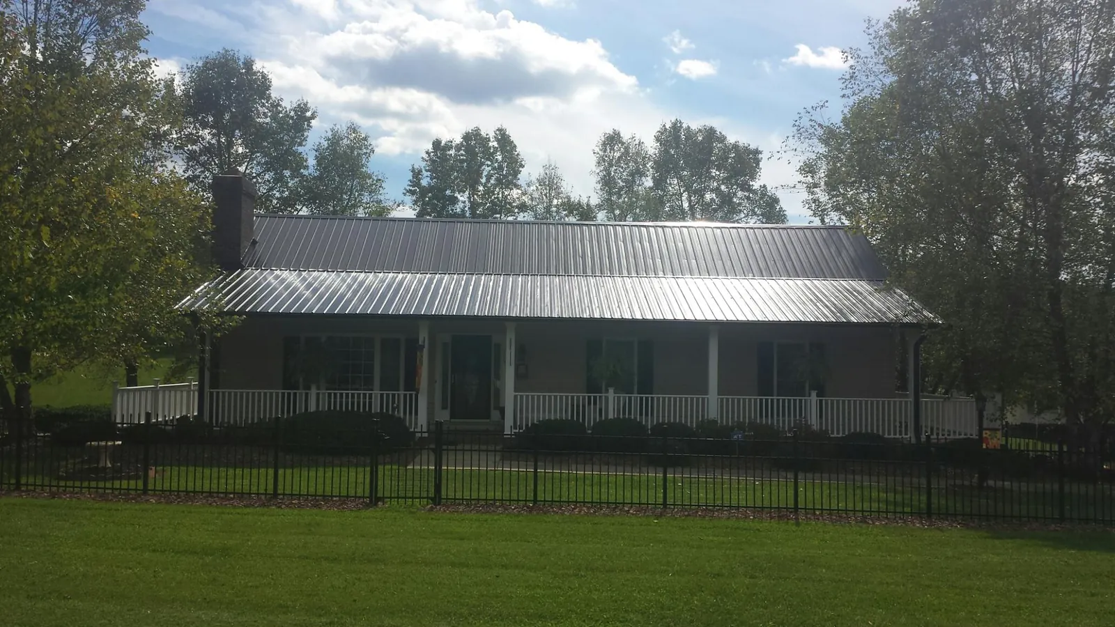 Gray metal roof on a brick ranch with a full width front porch — Gutter Guard Installation work by our crew in West Warwick