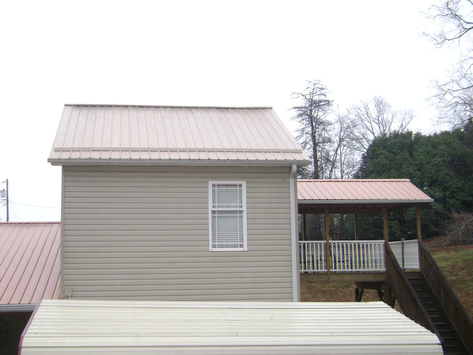Tan metal roofs on a two story addition and attached porch, from a Roof Replacement job in West Warwick