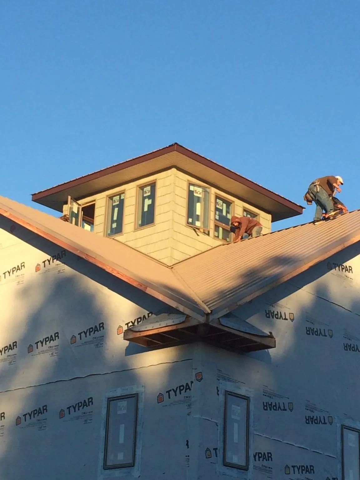 Roofers working around a rooftop cupola on a new metal roof at sunset — Roof Waterproofing in West Warwick by Roofing Brothers